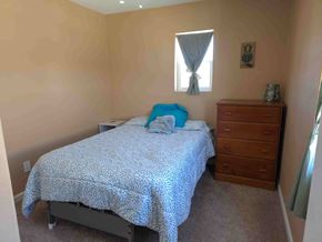 Walsenburg house for rent - A bedroom with a bed, dresser, and window.