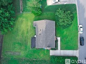Fuquay Varina house for rent - A house with a grey roof is surrounded by a green lawn.