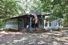 Eureka Springs house for rent - A house with a flag on the porch is surrounded by trees.