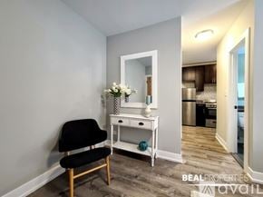 Chicago apartment for rent - A room with a chair, a mirror, and a table with flowers on it.