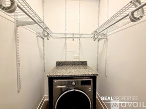 Chicago apartment for rent - A laundry room with a washer and dryer and a shelf above.