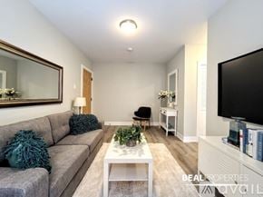 Chicago apartment for rent - A living room with a grey couch, a white coffee table, and a flat screen TV mounted on the wall.