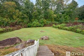 Raleigh house for rent - A wooden staircase leads to a grassy area with rocks and trees in the background.