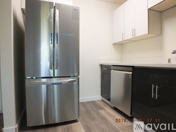 Seattle apartment for rent - A stainless steel refrigerator stands in a kitchen with white cabinets.