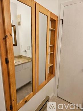 Fort Collins condo for rent - A wooden medicine cabinet with a mirror and a shelf is in the image.