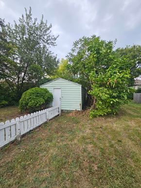 Lima house for rent - A green shed sits in a grassy yard next to a white picket fence.