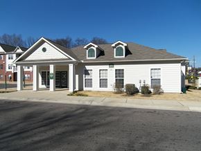 Memphis apartment for rent - A white building with a brown roof and a green sign on the front.