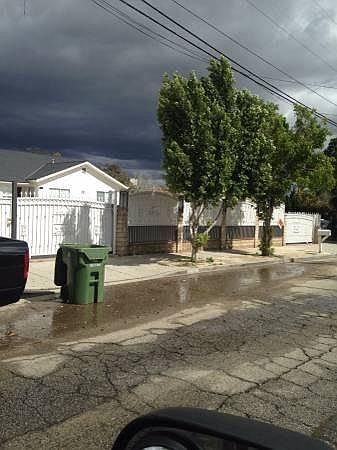 Sylmar house for rent - A car is parked on a street with a green trash can and a white house in the background.