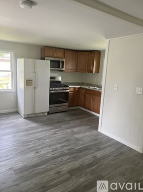 Black River apartment for rent - A kitchen with a white fridge, wooden cabinets, and a grey floor.