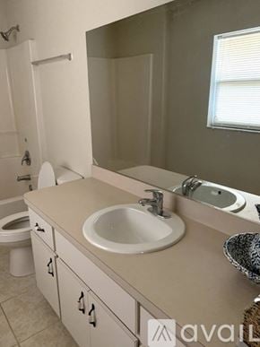 Ocala house for rent - A bathroom with a toilet, sink, and mirror.