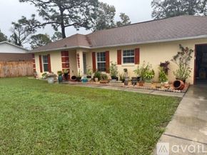 Ocala house for rent - A house with a red roof and a white wall with a garden in front.