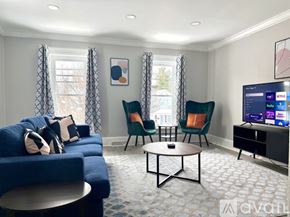 Watertown apartment for rent - A living room with a blue sofa, two chairs, and a television.