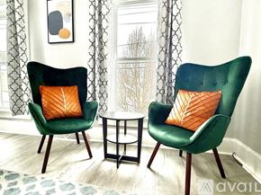 Watertown apartment for rent - Two green chairs with orange pillows in front of a window.