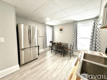 Watertown apartment for rent - A kitchen with a stainless steel refrigerator and a dining table with chairs.