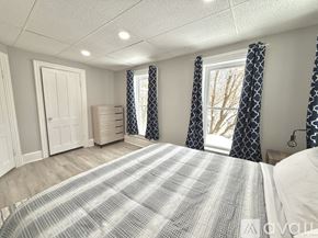 Watertown apartment for rent - A bedroom with a large bed and a window with curtains.