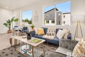 Monroe townhouse for rent - A modern living room with a grey couch, a glass coffee table, and a large window.