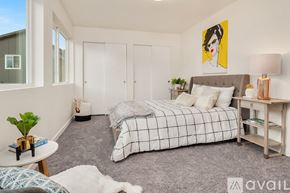 Monroe townhouse for rent - A bedroom with a bed, nightstand, and a painting of a woman's face on the wall.
