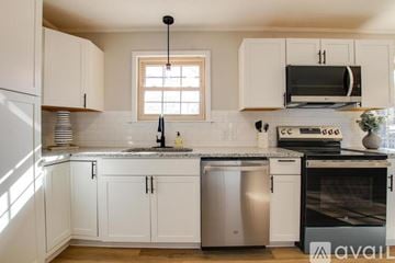 Athens house for rent - A kitchen with white cabinets and a granite countertop.