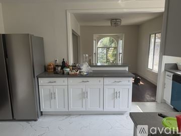 Compton house for rent - A kitchen with white cabinets and a grey countertop.
