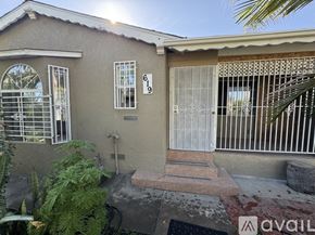 Compton house for rent - A house with a brown roof and a white door is surrounded by green plants.
