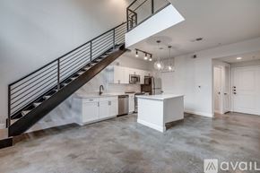 Dallas apartment for rent - A spacious, empty room with a staircase and a kitchen area.