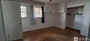 Highland house for rent - A room with wooden floors and white walls, with a window covered by a white curtain.