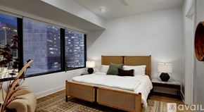 Dallas apartment for rent - A bedroom with a large bed and a city view through the window.
