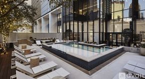Dallas apartment for rent - A modern outdoor pool area with sun loungers and a glass wall.