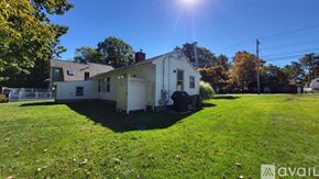 Wells house for rent - A house with a white exterior is surrounded by a grassy lawn and trees.