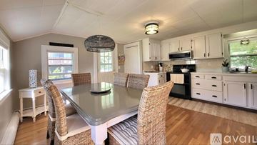 Wells house for rent - A kitchen with a table and chairs in the foreground and a window with a view of a garden outside.