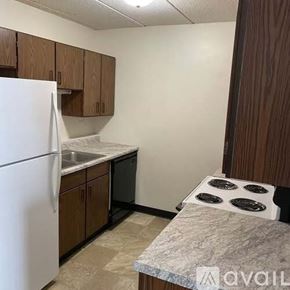 La Crosse apartment for rent - A kitchen with a white refrigerator, brown cabinets, and a marble countertop.