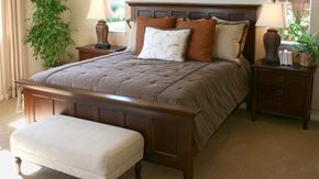 Toronto apartment for rent - A bed with a wooden headboard and footboard with a grey bedspread and a white pillow in the middle.