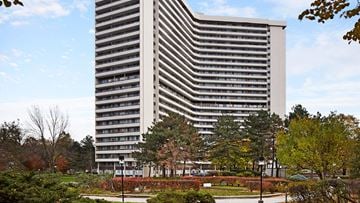 Toronto apartment for rent - A tall building with a striped facade is surrounded by trees and shrubbery.