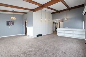 Edmonton apartment for rent - A spacious room with a carpeted floor and wooden beams on the ceiling.