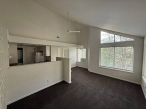 Boulder apartment for rent - A spacious, empty room with a large window and a staircase on the left side.