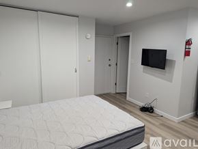 State College apartment for rent - A bedroom with a bed, a television, and a fire extinguisher on the wall.