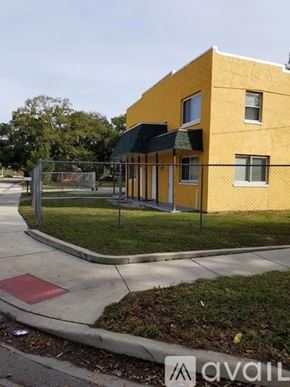 Orlando apartment for rent - A yellow building with a black awning and a metal fence in front.