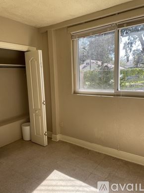 Orlando apartment for rent - A room with a door open to a hallway and a window with a view of a house and trees outside.