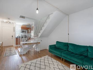 Miami apartment for rent - A living room with a green couch and a white staircase.
