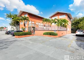 Miami apartment for rent - A building with a balcony and a parking lot in front.