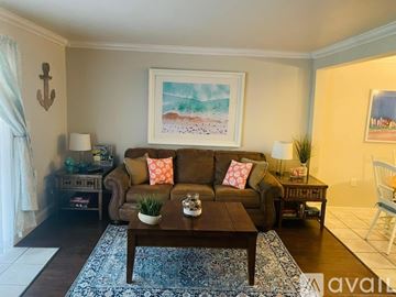 St. Petersburg house for rent - A living room with a brown couch, a coffee table, and a painting on the wall.