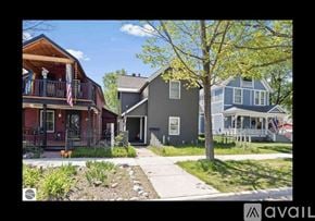 Traverse City apartment for rent - A row of houses with a tree in front of the grey house.