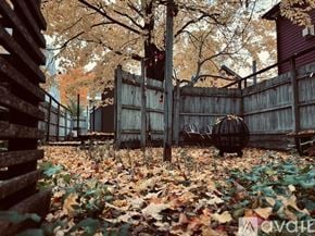 Traverse City apartment for rent - A wooden fence with a gate and a tree with brown leaves.