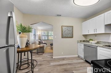 St. Petersburg house for rent - A kitchen with a refrigerator, a table with a plant on it, and a view of a living room through a window.
