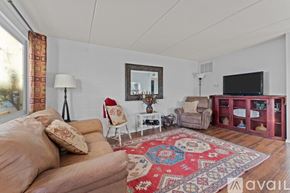 Wickenburg apartment for rent - A living room with a brown sofa, a red rug, and a flat screen TV.