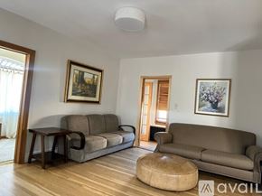 Long Beach house for rent - A living room with a grey couch, a brown ottoman, and two framed pictures on the wall.