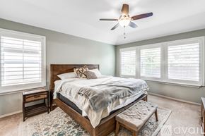 Schertz house for rent - A bedroom with a bed, a ceiling fan, and a window with blinds.