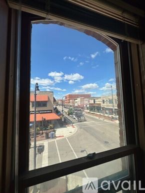 Dekalb apartment for rent - A view from a window looking out at a street with buildings and a clear sky.