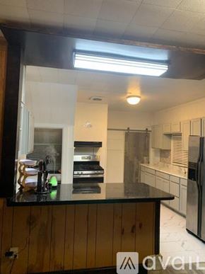 Magnolia house for rent - A kitchen with a black countertop and wooden cabinets.