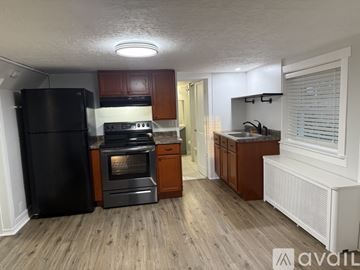 Berwyn apartment for rent - A kitchen with wooden floors and a black refrigerator.